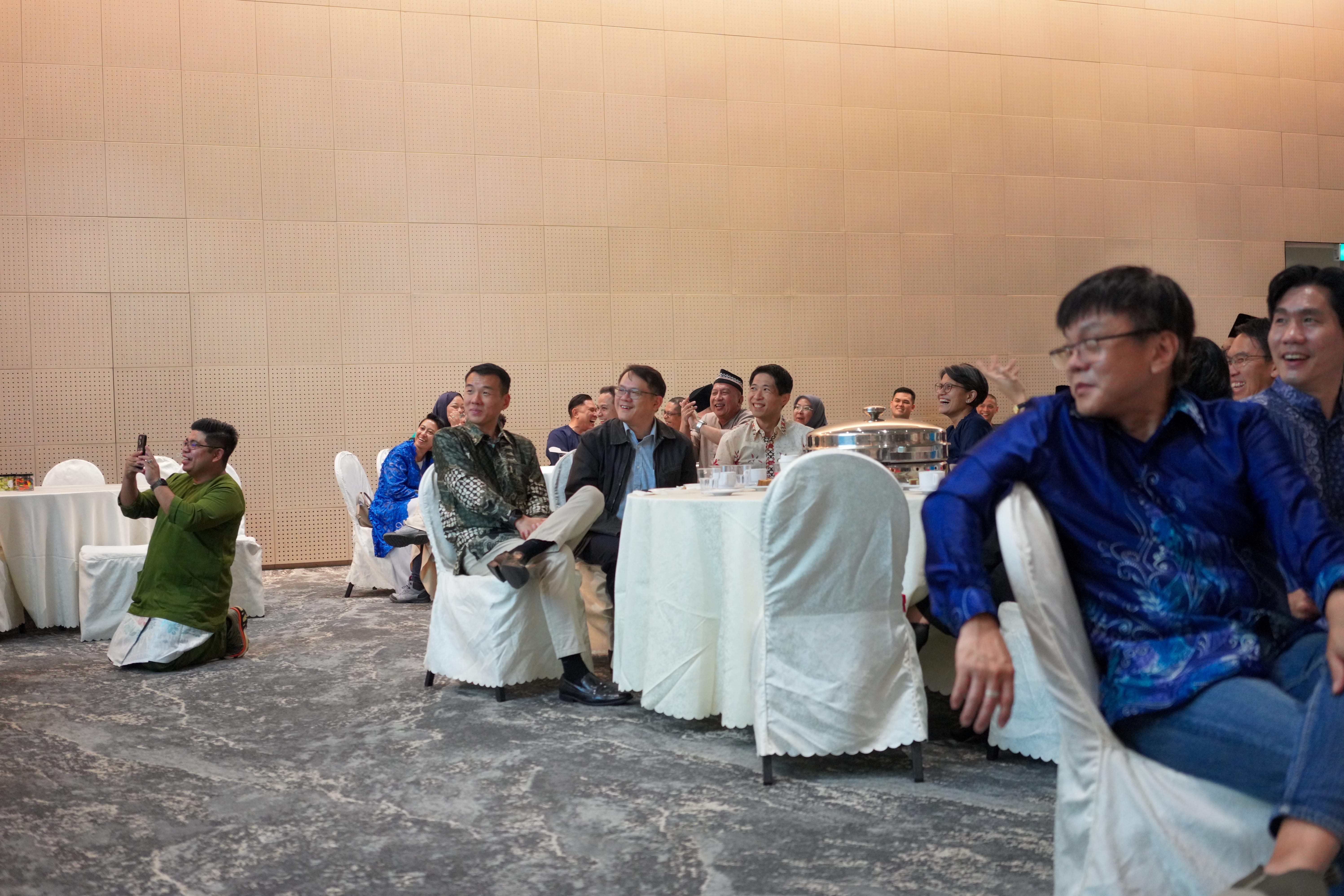 Guests seated around banquet tables laughing and reacting to an interactive performance in the function hall.